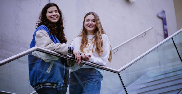 Two students on campus smiling at the camera.