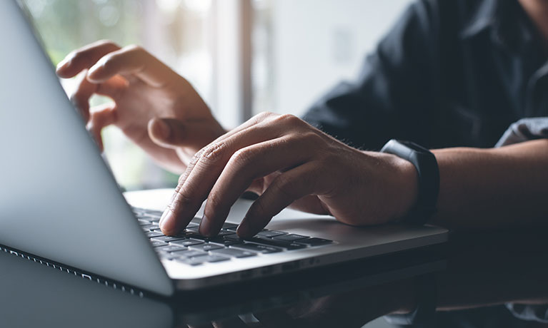 Someones hands typing on a laptop keyboard