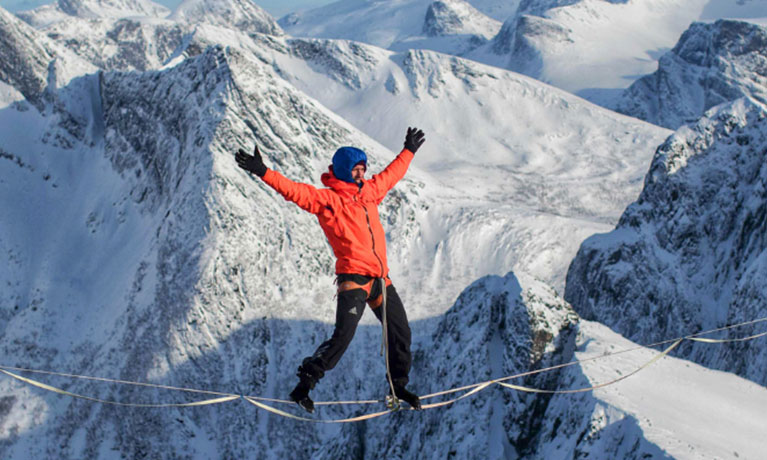 Adventurer walking across a rope ladder in the mountains