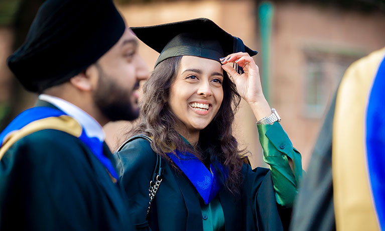 Female and male graduates outside in their graduation gown and cap