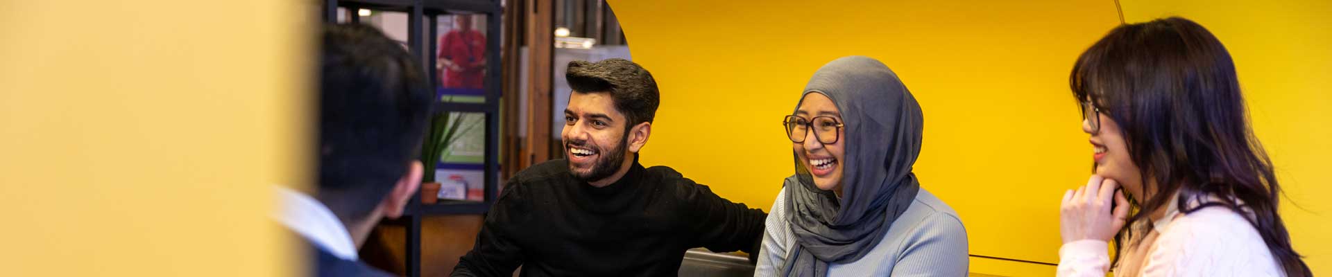 Three smiling students chat in a booth