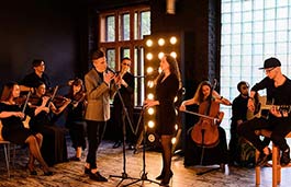 Group of musicians playing various instruments in the background behind with a male and female singers 