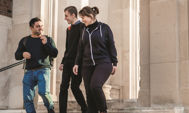 Three young adults going down an old buildings stairs