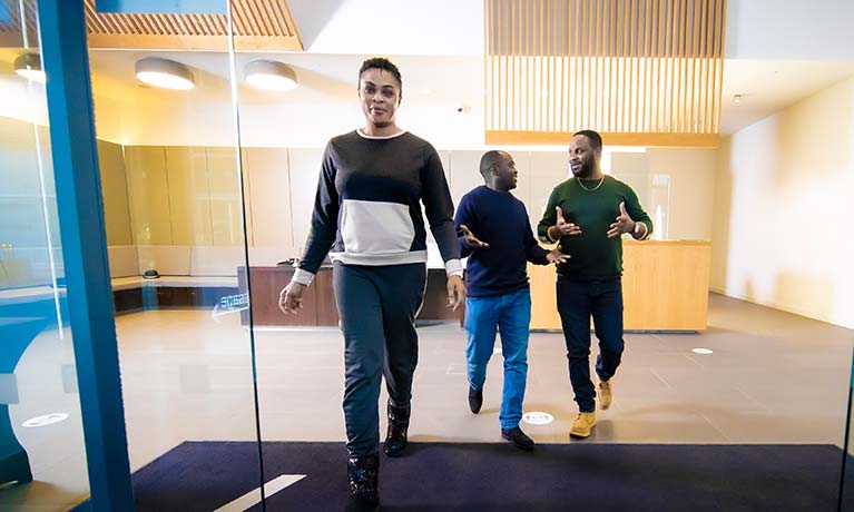 A group of students talking whilst walking out of a building