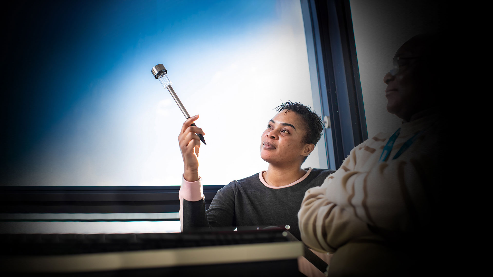 Student sat in front of a window holding a thin light