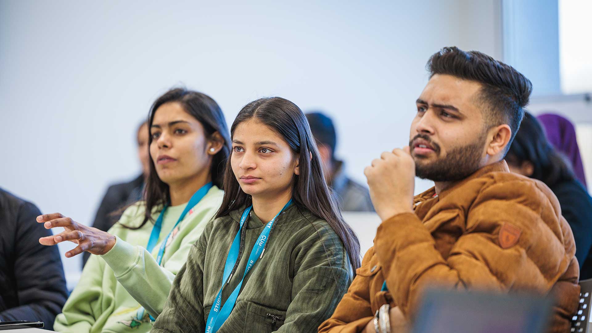 Three students sat in a classroom looking towards the front