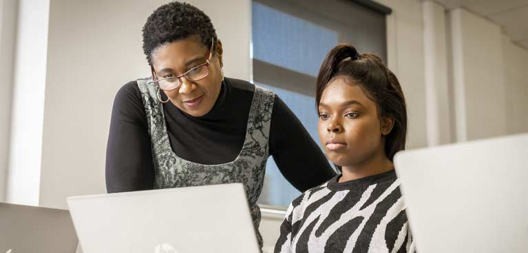 A woman on a laptop with another looking over her shoulder