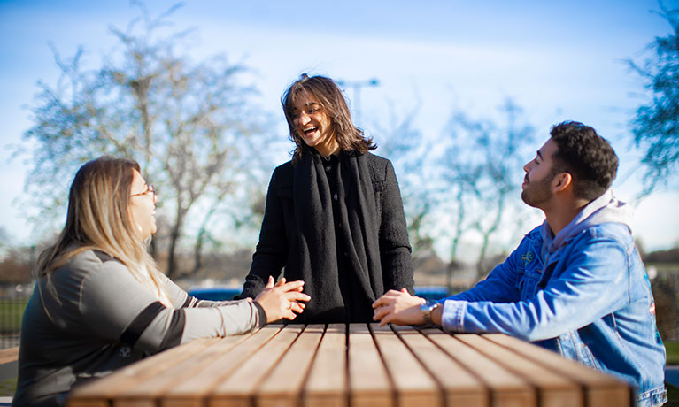 Students sitting and talking on a bench on a clear day