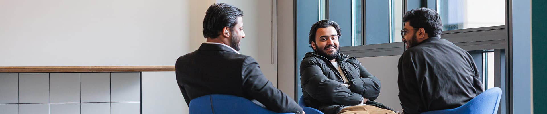 Group of males sat on chairs facing towards each other laughing