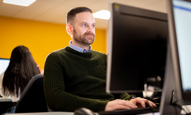 A student using a desktop computer in an open access IT suite.