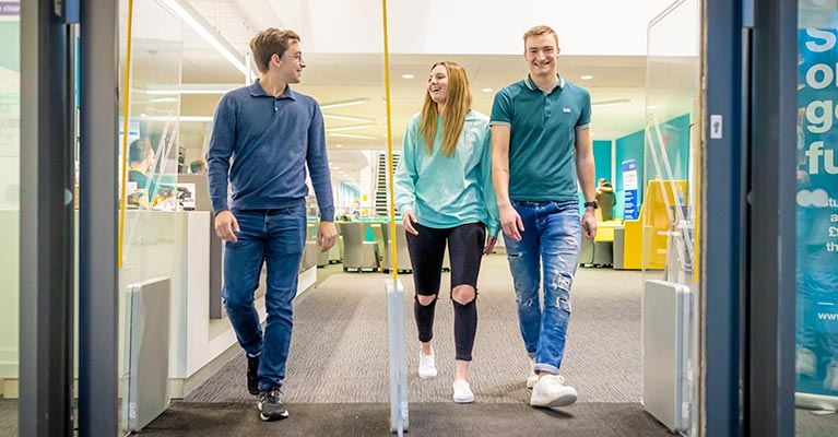 Three students walking out of the CU Scarborough building whilst talking