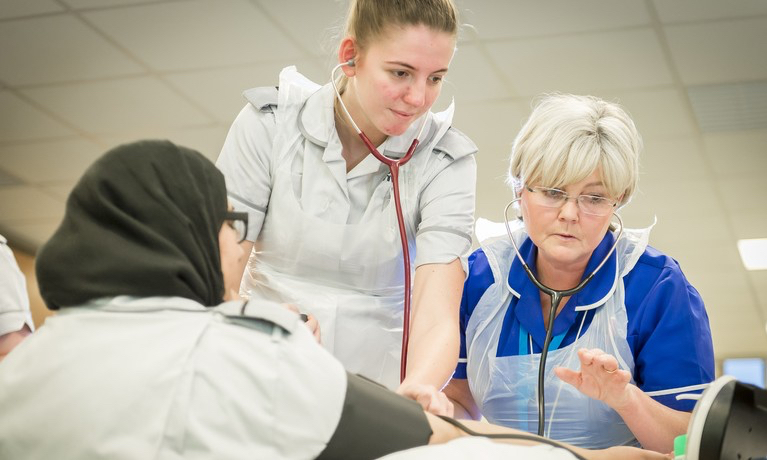 Two nurses helping a patient