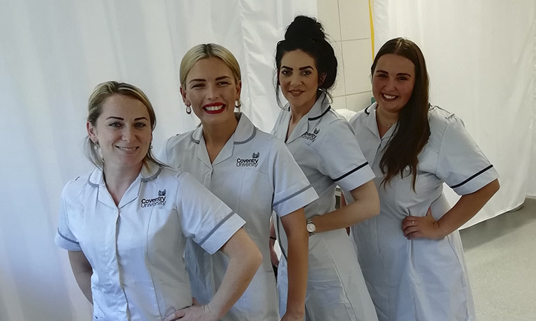 Four students show their Nursing uniforms