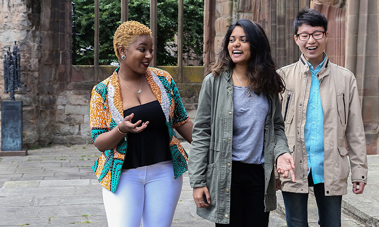 Three students walking through the cathedral ruins