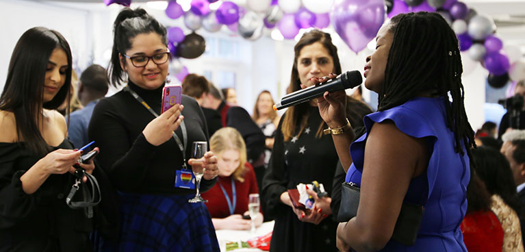 Lady singing and students watching at the awards ceremony