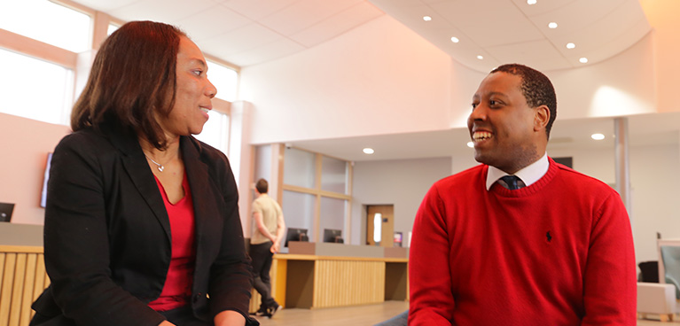 Two students sitting down inside and talking