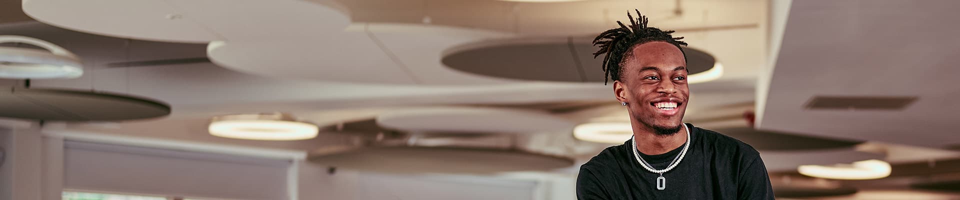 Male student sat on a table smiling