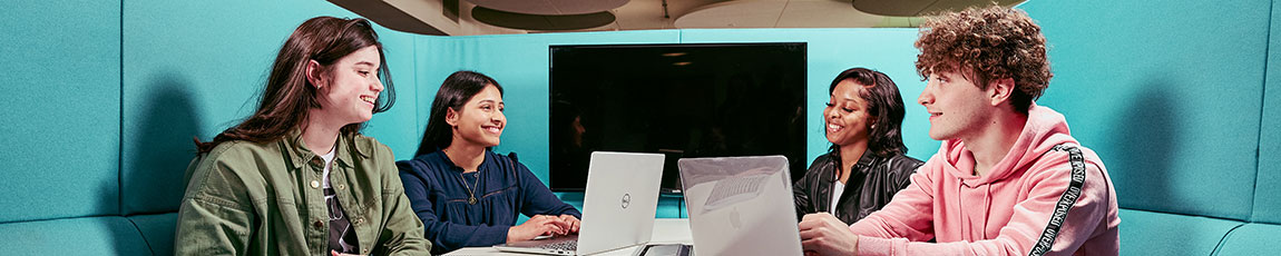 Four students sat in a pod working on their laptops