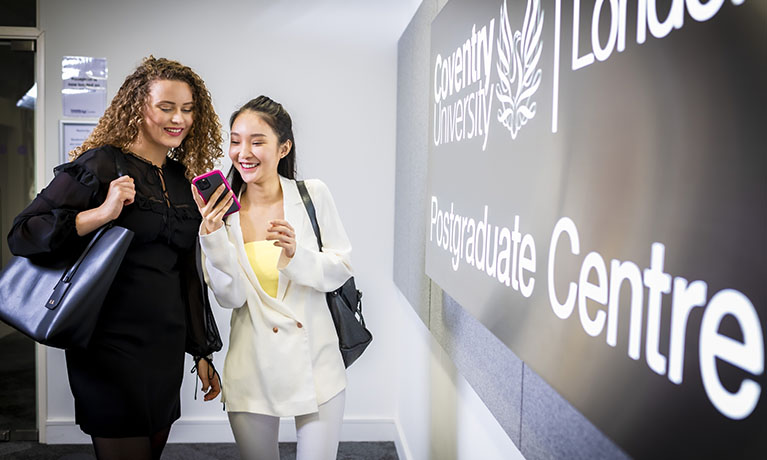 Two female students looking into mobile phone