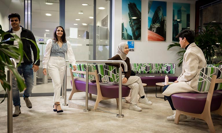 Two students walking through an open plan room