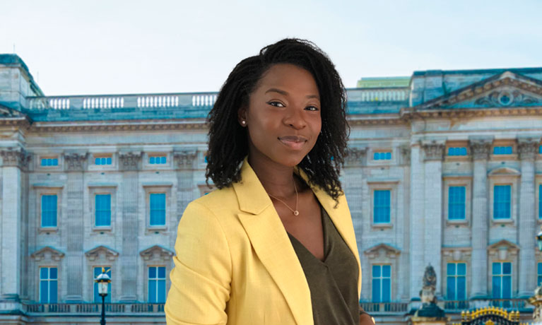 Young lady wearing a yellow jacket smiling in front of a London building