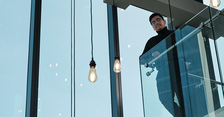 Young man looking over a glass wall