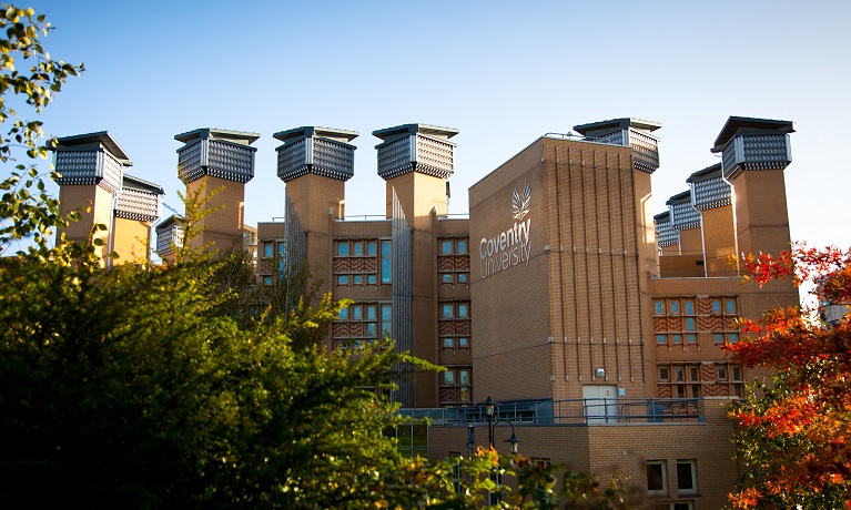 A shot of Coventry University's Lanchester Library with trees with green leaves in the foreground