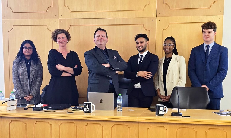 The three Coventry University students in smart dress alongside three representatives of Elite Law Solicitors in a mock courtroom
