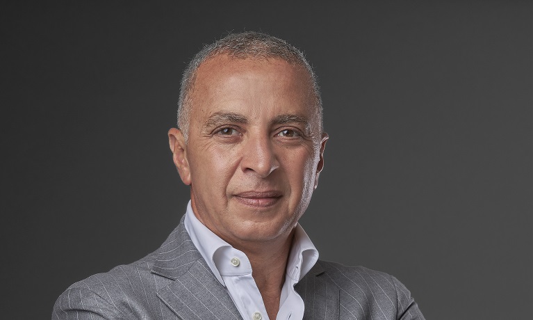 A head and shoulders image of Eng Ahmed El Sewedy wearing a white shirt and grey suit smiling at the camera