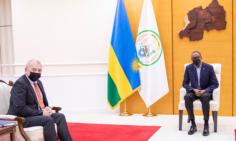 Two men wearing masks sitting close to each other with flags in the background