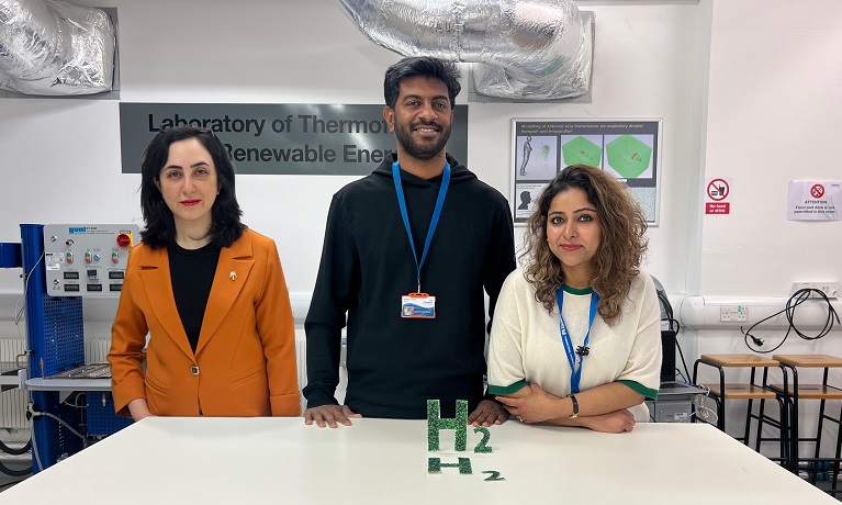 Dr Mahshid Yazdi Far, Dr Jayesh Shanthi Bhavan and Dr Maria Tareen stood in a science lab with a green hydrogen symbol on the table infront of them