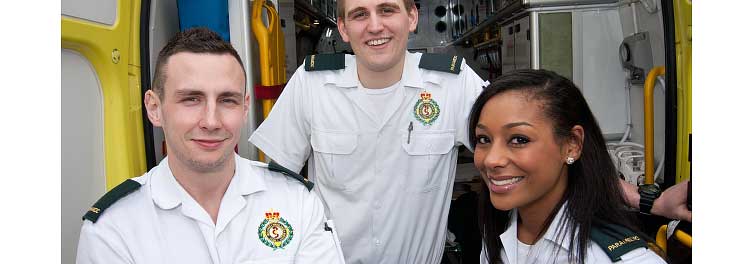 A portrait of Three Ambulance staff stood outside the Ambulance van