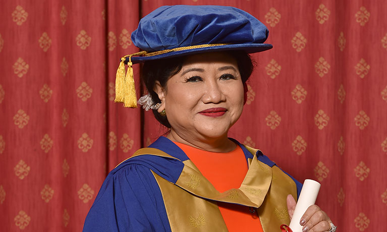 Woman wearing ceremonial robes holding a certificate