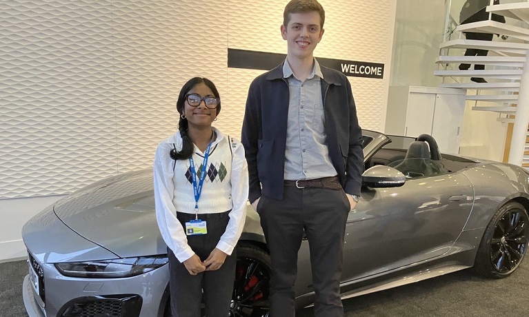 A male and female student standing next to a car