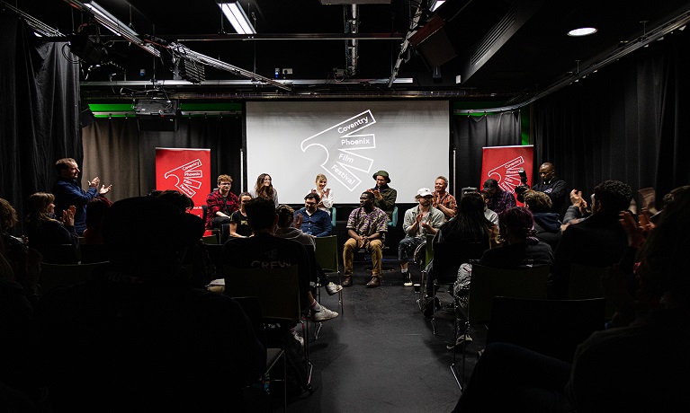 An audience facing a discussion panel on a stage