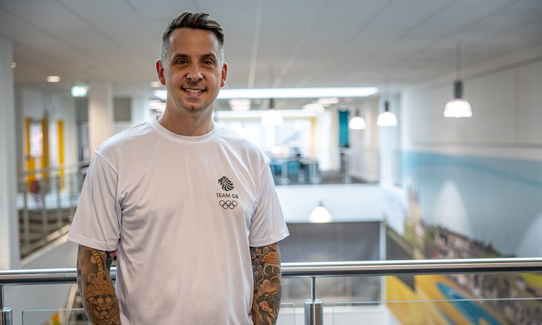 Adam Whitehead wearing a white Team GB T-shirt stood inside the CU Scarborough campus building