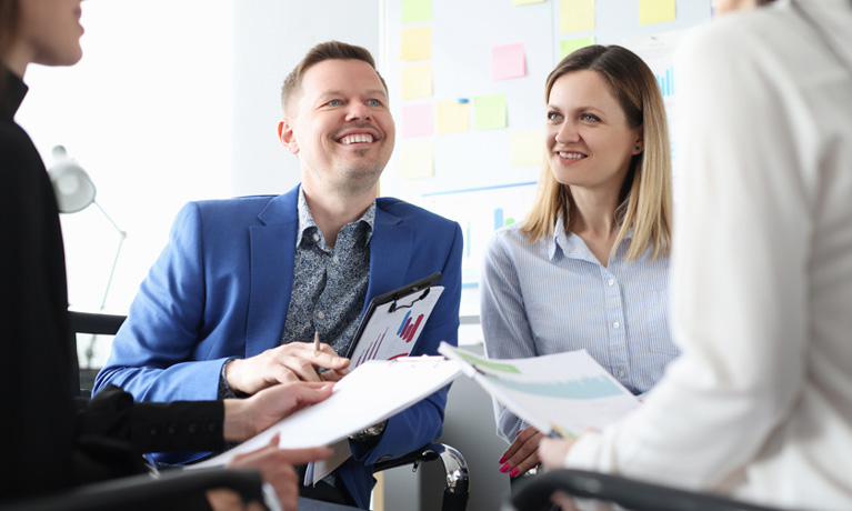 Four professionals holding paperwork and sat in a circle.