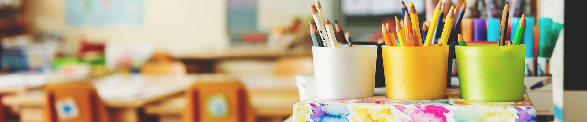 Pots of coloured pencils and pens in a primary school classroom