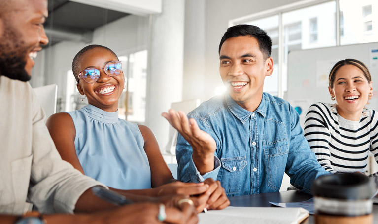 Teachers in a classroom sitting around a laptop talking.