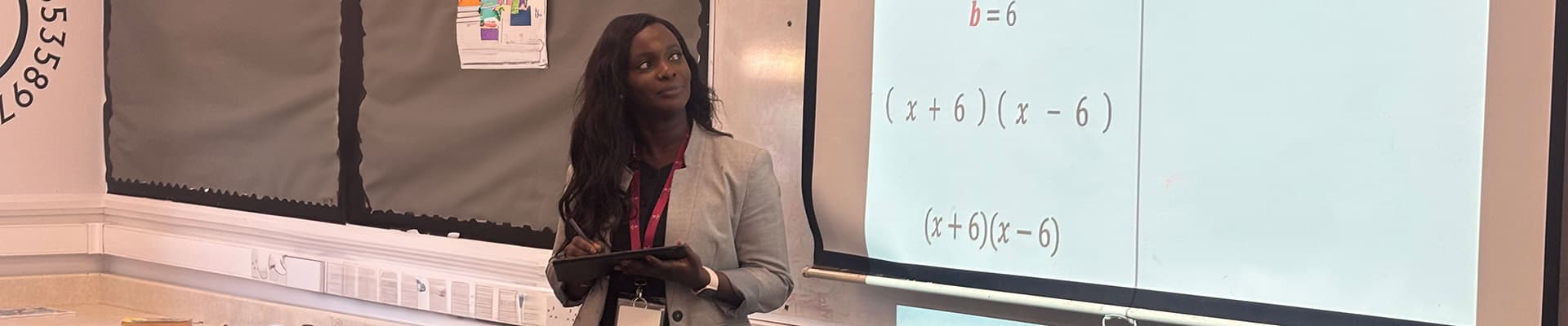 Haddy Jeng standing in front of a whiteboard with algebra looking at the screen