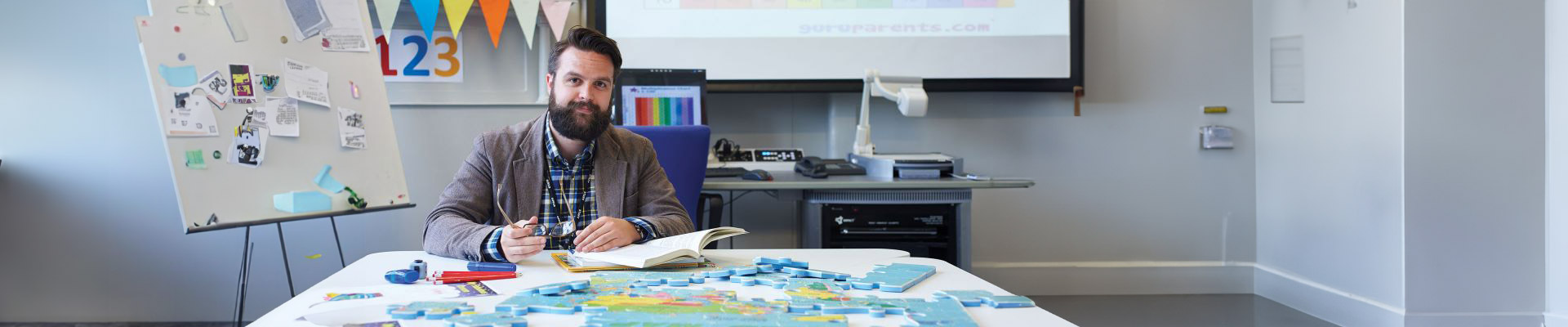 Matthew Tragheim sat in a classroom with a whiteboard behind him and colourful bunting.