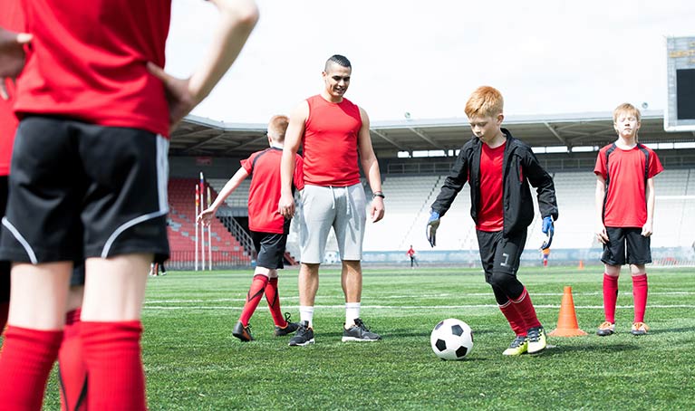 Football players in red kit on a football pitch.