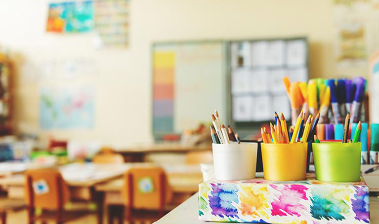 A classroom with paint brushes chairs and whiteboard