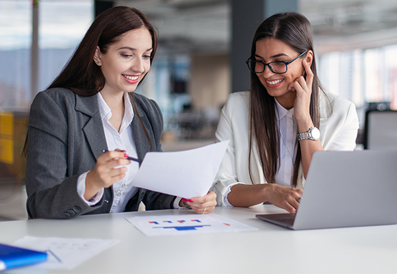 Two women dressed in professional workwear going over some paperwork.