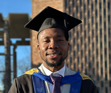 Chidindu Ojimadu wearing a graduation cap and gown at his graduation ceremony, smiling at the camera.