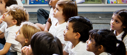 A group of primary school children sat on the floor in a classroom