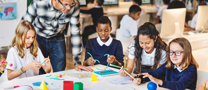 A teacher and students in the classroom sat around a large table, with materials in front of them