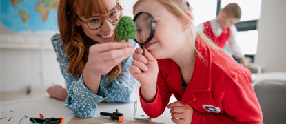 A primary school student with Down syndrome with a teacher, programming electric toys and robots in a classroom
