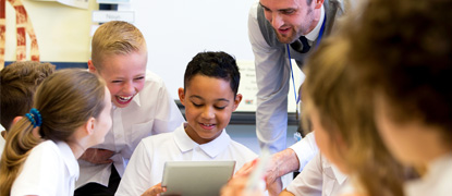 A male teacher working with students using a tablet