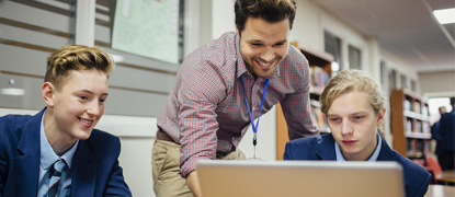 A male teacher helping a student using a laptop